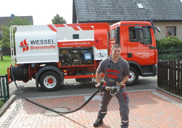 Ein Mitarbeiter von uns posiert mit einem Heizölschlauch vor einem Firmen-Lkw.