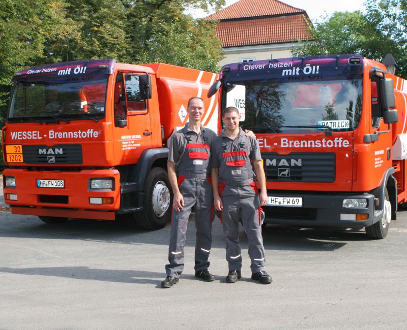 Marko Wessel steht mit einem seiner Mitarbeiter in Arbeitskleidung vor zwei Firmen-Lkw.